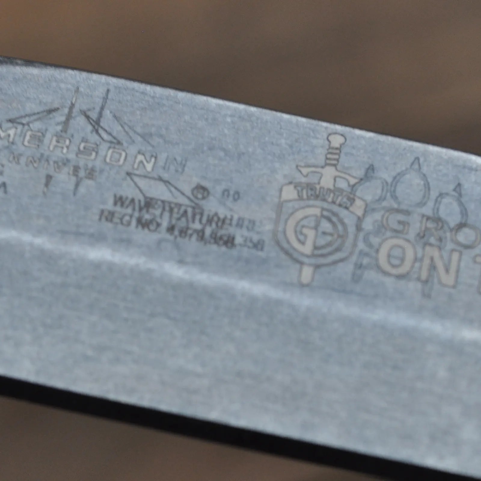 The Sheepdog A TF - Old Logo behind New Logo by Emerson Knives, Inc. is a folding pocket knife with a black handle and stonewashed blade marked CONTRUTH, shown on wood. This item is offered as Final Sale.