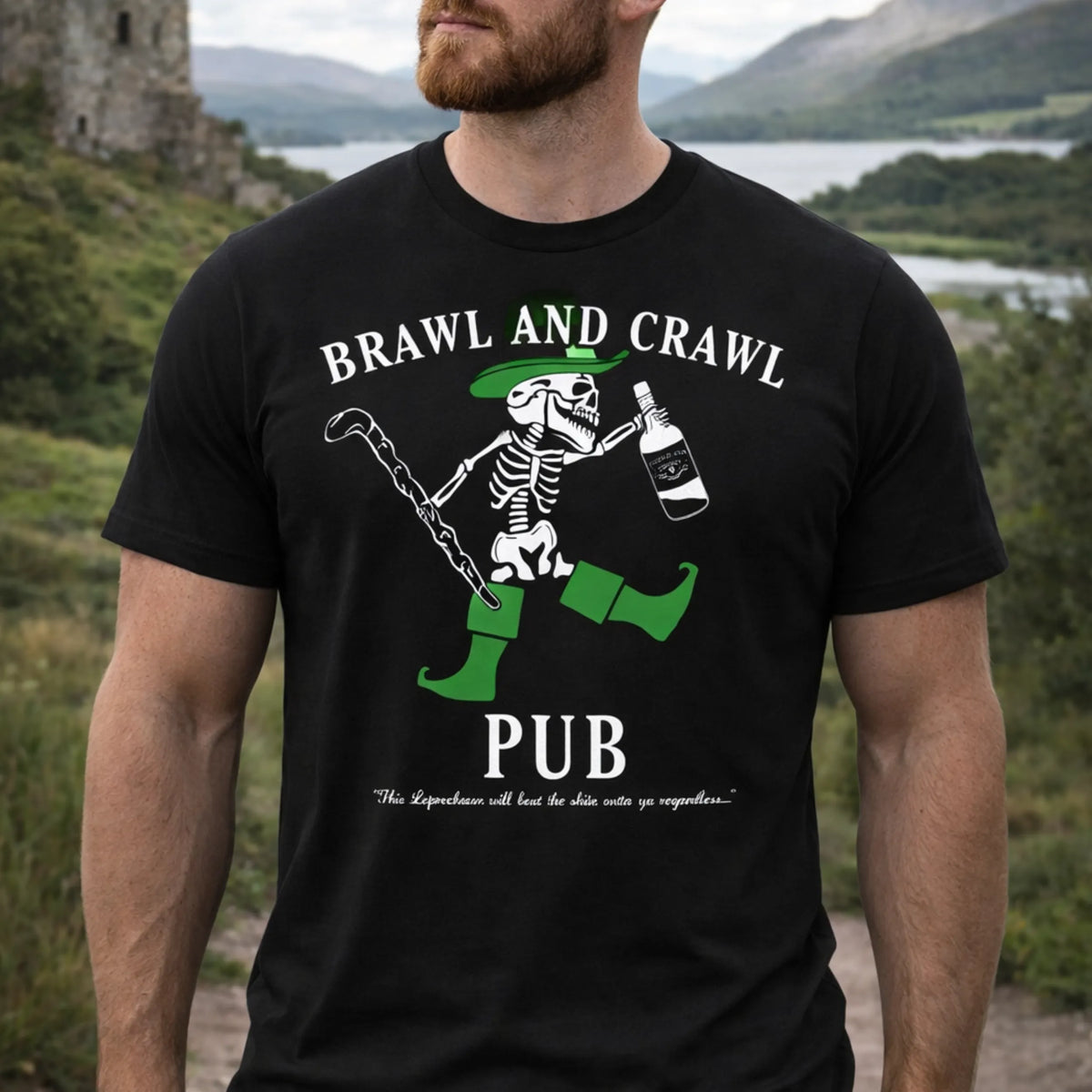 A man wears the Emerson Knives, Inc. Brawl and Crawl Pub T-Shirt, featuring a cartoon skeleton leprechaun with cane and bottle, green boots, hat, hills and water background, and the Irish saying "Slainte.
