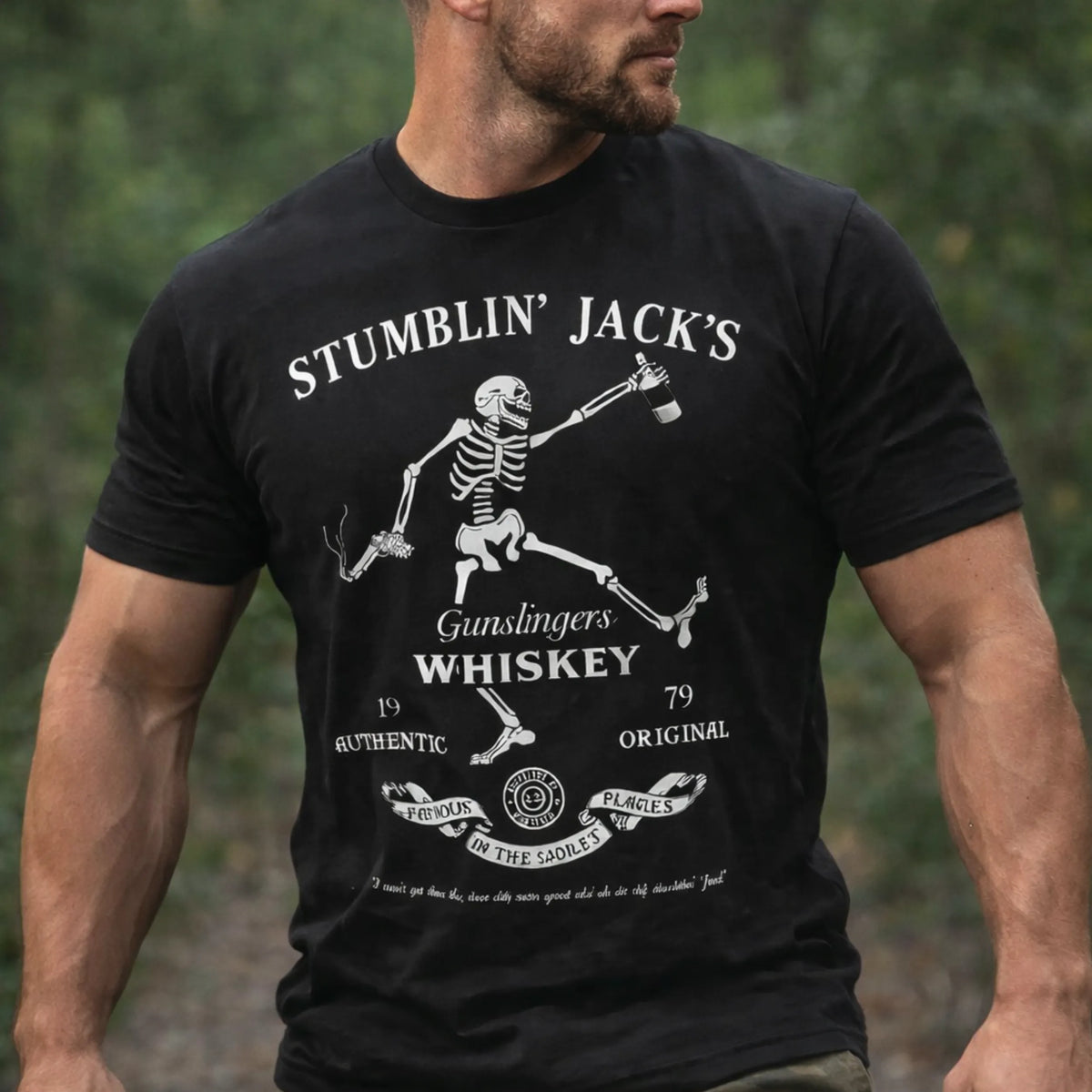A man wears the Emerson Knives, Inc. Stumblin' Jack T-Shirt featuring a black graphic of a dancing skeleton with a bottle and gun, plus text reading "Stumblin Jacks Gunslingers Whiskey" and decorative designs.