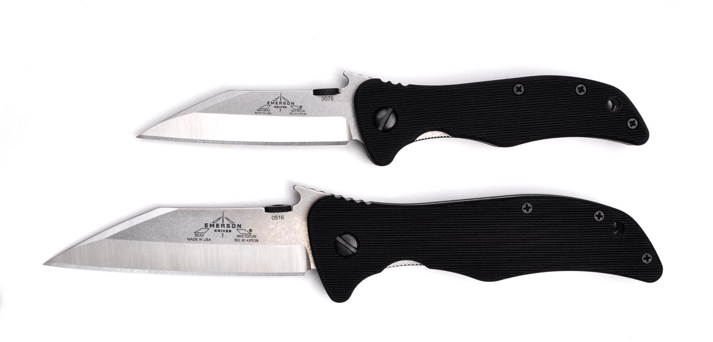 The Emerson Knives, Inc. Mini Seax is a folding utility blade with a black textured handle and a partially open silver tanto-style blade, inspired by the Viking Seax knife and featuring engraved text and logos near the handle.