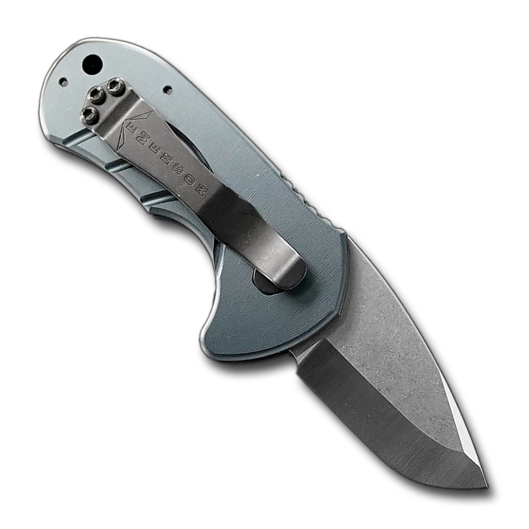 The Bullshark Auto by Emerson Knives, Inc. is a compact folding pocket knife with a silver grooved handle, short stainless steel blade, and a small red button for easy automatic-style use—perfect for everyday carry.