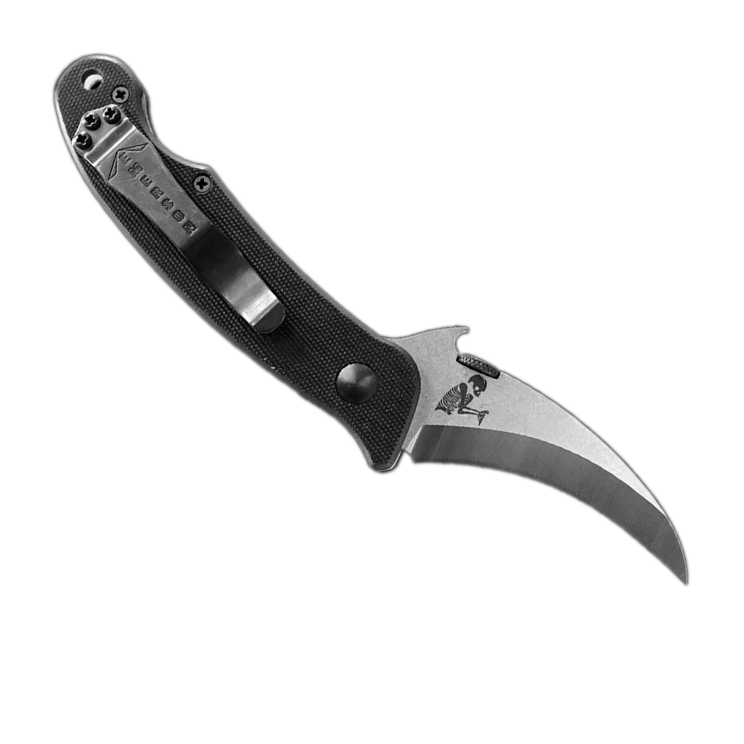 The Emerson Knives, Inc. Elvia is a folding karambit knife with a curved stainless steel blade and textured black handle, shown on a white background—ideal as both a survival tool and for personal protection.