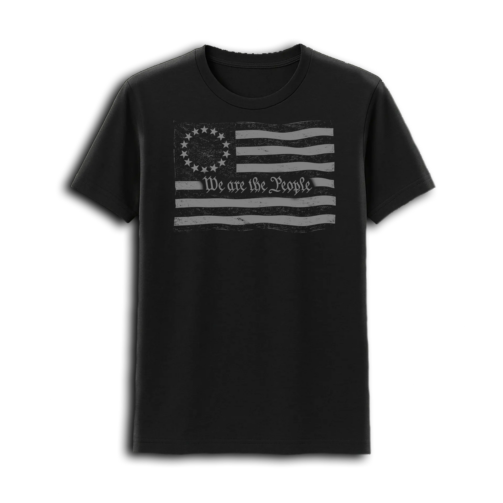 At sunset outdoors, a muscular man with tattooed arms wears the Emerson Knives, Inc. We Are the People T-Shirt featuring a distressed Betsy Ross flag and “We the People.” Military helicopters and sandbags are seen in the background.